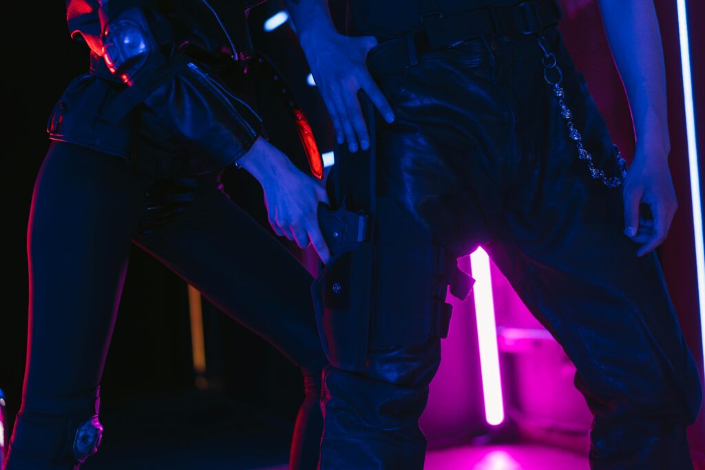 Two people in dark, neon-lit room holding weapons, creating a dramatic scene.